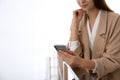 Young woman using modern smartphone indoors. Space for text Royalty Free Stock Photo