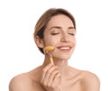 Young woman using natural jade face roller on white background