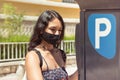 Young woman using parking ticket machine. Close up photography of a woman wearing facial mask paying for parking Royalty Free Stock Photo