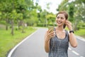 Young woman using phone for listening to music. Fitness runner girl listening to music with earphones on phone wearing smartwatch.