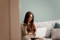 Young woman using phone and working at laptop computer at home, beautiful girl shopping or chatting online in social network, Royalty Free Stock Photo