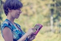 Young woman using a pink tablet outdoors