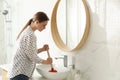 Young woman using plunger to unclog sink drain Royalty Free Stock Photo