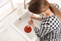 Young woman using plunger to unclog sink drain in kitchen, above view Royalty Free Stock Photo