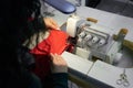 Young woman using professional overlock sewing machine in workshop studio. Equipment for edging, hemming or seaming