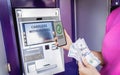 Young woman using the smart phone for cardless withdrawing the cash near the ATM