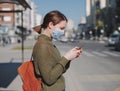 Young woman using smart phone in the city wearing face mask for air pollution, flu, virus, influenza, coronavirus