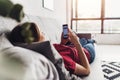 Young woman using smart phone while lying on the couch at home Royalty Free Stock Photo