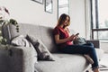 Young woman using smart phone while relaxing on couch at living room