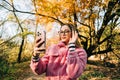 Young woman using smartphone in autumn park , heaving video call, communicate with friends or family Royalty Free Stock Photo