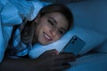 Young woman using smartphone in bed at night. Nomophobia and sleeping disorder problem Royalty Free Stock Photo
