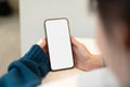 Young woman using smartphone blank screen frameless modern design while lying on the bed in home interior Royalty Free Stock Photo