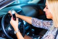 Young woman using a smartphone while driving a car Royalty Free Stock Photo