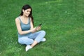 Young woman using smartphone on green grass outdoors Royalty Free Stock Photo