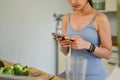 Young woman using smartphone while he preparing vegan healthy breakfast in kitchen Royalty Free Stock Photo