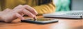 Young woman using smartphone while she working on laptop in the shop covered on a warmlight day. Royalty Free Stock Photo