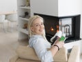 Young woman using tablet computer in front of fireplace Royalty Free Stock Photo