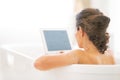 Young woman using tablet pc in bathtub. rear view