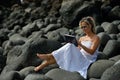 Young woman using tablet on rocky beach Royalty Free Stock Photo