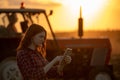Young woman using tablet to monitor field work in front of tractor at sunset Royalty Free Stock Photo