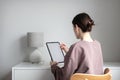 Young woman using tablet for working from home during covid-19 lockdown. Simple scandinavian living room interior