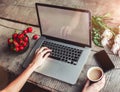 Workspace with girl`s hands, laptop computer, bouquet of peonies flowers, coffee, strawberries Royalty Free Stock Photo