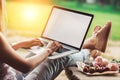 Young woman using and typing laptop computer at rough wooden table with coffee cup, strawberries, bouquet of peonies flowers Royalty Free Stock Photo