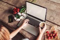 Young woman using and typing laptop computer at rough wooden table with coffee cup Royalty Free Stock Photo