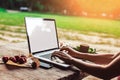 Young woman using and typing laptop computer at rough wooden table with coffee cup, strawberries, bouquet of peonies flowers, Royalty Free Stock Photo