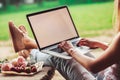 Young woman using and typing laptop computer at rough wooden table with coffee cup, strawberries, bouquet of peonies flowers, Royalty Free Stock Photo