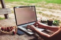 Young woman using and typing laptop computer at rough wooden table with coffee cup, strawberries, bouquet of peonies flowers Royalty Free Stock Photo