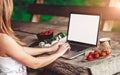 Young woman using and typing laptop computer at rough wooden table with coffee cup Royalty Free Stock Photo