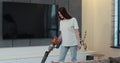 Young woman using vacuum cleaner to clean floor in the living room at home. Cleaning home by using wireless vacuum Royalty Free Stock Photo