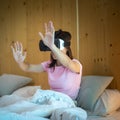 Young woman using virtual reality headset in bed. VR, Future digital technology, game, movies entertainment, metaverse, NFT and 3D Royalty Free Stock Photo