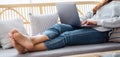 A young woman using and working on laptop computer while lying on a sofa at home Royalty Free Stock Photo