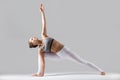 Young woman in Utthita parsvakonasana pose, grey studio backgrou