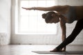 Young woman in Utthita Trikonasana pose, white loft studio, clos