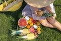 Young woman with various delicious fruits on summer picnic in park