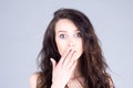 Young woman with very large eyes in surprise covers mouth with hand Royalty Free Stock Photo