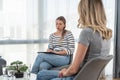 Young woman victim of domestic violence or robbery or mobbing at work talks to an expert psychotherapist for therapy in a comforta Royalty Free Stock Photo