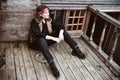 A young woman in vintage black clothes sits on a wooden floor with a knife in her hands Royalty Free Stock Photo