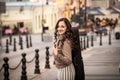 Young woman with a violin case smiling againgt a street