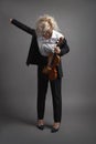 Young woman violinist in a black male suit with a violin putting on her jacket Royalty Free Stock Photo