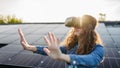 Young woman with virtual goggles on the roof with solar panels.