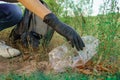 Young woman volunteer collects trash in trash bag rubbish in nature