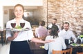 Young woman waiter bringing order for guests in country cafe Royalty Free Stock Photo