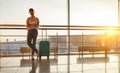 young woman waiting for flying at airport at window with suitcase Royalty Free Stock Photo