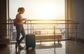 young woman waiting for flying at airport at window with suitcase . Royalty Free Stock Photo