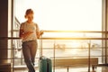 young woman waiting for flying at airport at window with suitcase Royalty Free Stock Photo