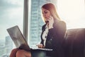 Young woman waiting in a hall sitting in modern office working on laptop talking on the phone Royalty Free Stock Photo